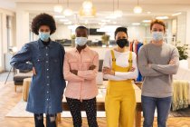 Ritratto di diversi gruppi di creativi che indossano maschere facciali al lavoro, guardando alla macchina fotografica. lavorare nel business creativo in un ufficio moderno durante la pandemia di coronavirus. — Foto stock