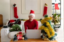 Albino african american man wearing santa hat making video call with christmas decorations. christmas, festivity and communication technology festivity and communication technology. — Stock Photo