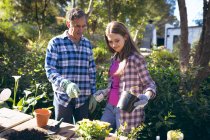 Happy caucasian grandfather and granddaughter gardening and planting. family time, active and healthy retirement lifestyle at home and garden. — Stock Photo