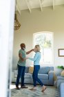 Glückliches Senioren-Paar im Wohnzimmer beim gemeinsamen Tanzen. Lebensstil im Ruhestand, Zeit zu Hause verbringen. — Stockfoto