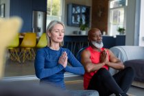 Glückliches älteres Paar in Turnkleidung, das gemeinsam Yoga praktiziert, meditiert. gesunder, aktiver Lebensstil im Ruhestand zu Hause. — Stockfoto