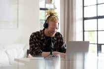 Homem americano africano albino feliz com dreadlocks trabalhando em casa e fazendo podcast. trabalho remoto usando a tecnologia em casa. — Fotografia de Stock