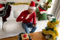 Albino-afrikanisch-amerikanischer Mann mit Weihnachtsmütze macht Videoanruf mit Weihnachtsdekoration. Weihnachten, Fest und Kommunikationstechnologie Fest und Kommunikationstechnik. — Stockfoto