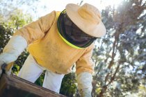 Homem idoso caucasiano usando uniforme de apicultor segurando um favo de mel. conceito de apicultura, apiário e produção de mel. — Fotografia de Stock