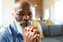Retrato de homem afro-americano sênior pensativo na sala de estar segurando bengala ambulante. estilo de vida da aposentadoria, passar tempo em casa. — Fotografia de Stock