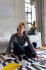 Albino-amerikanischer Mann sitzt auf dem Boden und arbeitet von zu Hause aus mit Laptop. Fernbedienung mit Technologie zu Hause. — Stockfoto