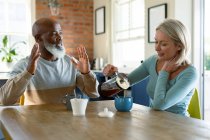 Щаслива старша різноманітна пара на кухні сидить за столом, п'є каву. пенсійний спосіб життя, проводити час вдома . — стокове фото