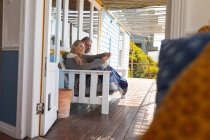 Heureux couple caucasien assis sur la terrasse ensoleillée. profiter du temps libre à la maison front de mer. — Photo de stock