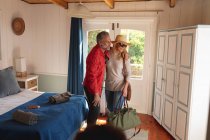 Счастливая кавказская взрослая пара с чемоданами, идущими в гостиничный номер. свободное время, путешествия и праздники. — стоковое фото