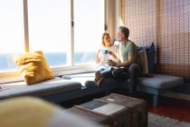 Glückliches kaukasisches reifes Paar, das im Wohnzimmer Kaffee trinkt. Freizeit zu Hause genießen. — Stockfoto