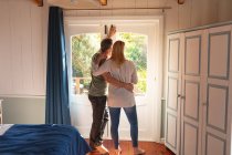 Щаслива біла зріла пара в спальні дивиться через вікно. насолоджуючись дозвіллям вдома . — стокове фото