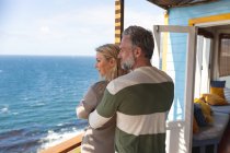 Couple caucasien reposant debout sur une terrasse au bord de la mer. profiter du temps libre à la maison front de mer. — Photo de stock