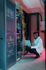 Африканський американський фахівець з комп'ютерних технологій використовує ноутбук для роботи в бізнес-серверах. Digital information storage and communication network technique. — стокове фото