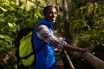 Homme afro-américain souriant avec sac à dos randonnée à la campagne. mode de vie sain et actif en plein air et temps libre. — Photo de stock