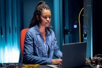 African american female computer technician using laptop working in server room. digital information storage and communication network technology. — Stock Photo