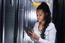 African american female computer technician using tablet working in server room. digital information storage and communication network technology. — Stock Photo