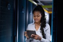 African american female computer technician using tablet working in server room. digital information storage and communication network technology. — Stock Photo