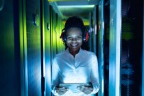 Afroamerikanische Computertechnikerin mit Kopfhörer und Tablet im Serverraum. digitale Informationsspeicherung und Kommunikations-Netzwerktechnologie. — Stockfoto