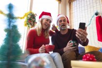 Glückliches kaukasisches reifes Paar, das Kaffee trinkt und zu Weihnachten ein Videotelefonat macht. Weihnachten, Fest und Kommunikationstechnologie. — Stockfoto