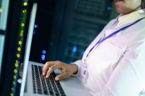 Close-up de afro-americana técnica de computador feminino usando laptop trabalhando na sala de servidores. armazenamento digital de informações e tecnologia de rede de comunicação. — Fotografia de Stock