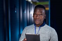 Tecnico informatico afroamericano di sesso maschile che utilizza tablet che lavora nella sala server. tecnologia digitale di memorizzazione delle informazioni e rete di comunicazione. — Foto stock