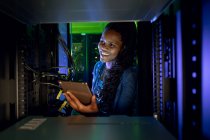 Glückliche afrikanisch-amerikanische Computertechnikerin, die mit dem Tablet arbeitet und im Serverraum arbeitet. digitale Informationsspeicherung und Kommunikations-Netzwerktechnologie. — Stockfoto
