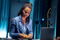 Tecnico informatico afroamericano femminile che utilizza laptop che lavorano nella sala server. tecnologia digitale di memorizzazione delle informazioni e rete di comunicazione. — Foto stock