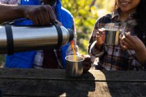 Casal diverso bebendo café e fazendo uma pausa de caminhadas no campo. saudável, estilo de vida ao ar livre ativo e tempo de lazer. — Fotografia de Stock