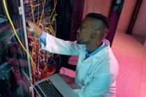 African american male computer technician using laptop working in business server room. digital information storage and communication network technology. — Stock Photo