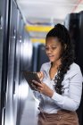 Eine afroamerikanische Computertechnikerin arbeitet mit einem Tablet im Serverraum. digitale Informationsspeicherung und Kommunikations-Netzwerktechnologie. — Stockfoto