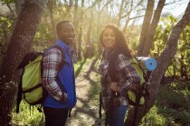 Feliz casal diversificado com mochilas caminhadas no campo. saudável, estilo de vida ao ar livre ativo e tempo de lazer. — Fotografia de Stock
