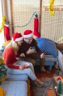Счастливая белая взрослая пара пьет кофе, делает видео-звонок на Рождество. Рождество, праздник и коммуникационные технологии. — стоковое фото