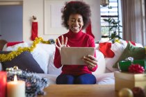 Heureuse femme afro-américaine en chapeau de Père Noël faisant tablette appel vidéo de Noël. Noël, fête et technologie de la communication. — Photo de stock