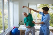 Biracial male physiotherapist treating back of senior male patient at clinic. senior healthcare and medical physiotherapy treatment. — Stock Photo