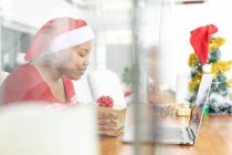 Glückliche afrikanisch-amerikanische Plus-Size-Frau mit Weihnachtsmütze macht Weihnachtsvideo-Anruf auf Laptop. Weihnachten, Fest und Kommunikationstechnologie. — Stockfoto