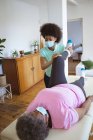 Eine afroamerikanische Physiotherapeutin behandelt eine ältere Patientin mit Gesichtsmasken in einer Klinik. Senior Health und medizinische physiotherapeutische Behandlung. — Stockfoto