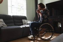 Продуманий інвалідний чоловік сидить на інвалідному візку п'є каву вдома. концепція інвалідності та переваги — стокове фото