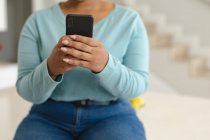 Midsection da afro-americana plus size mulher ter chamada de vídeo no smartphone na cozinha. estilo de vida, lazer, passar tempo em casa com a tecnologia. — Fotografia de Stock