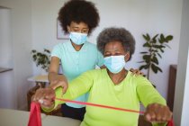 Fisioterapeuta afro-americana tratando a paciente idosa com máscaras faciais na clínica. cuidados de saúde seniores e tratamento de fisioterapia médica. — Fotografia de Stock