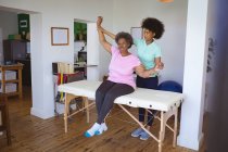 Afroamerikanische Physiotherapeutin, die eine ältere Patientin in der Klinik behandelt. Senior Health und medizinische physiotherapeutische Behandlung. — Stockfoto