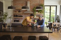 Der erwachsene Sohn und der ältere Vater trinken Kaffee in der Küche. Familienzeit zu Hause zusammen. — Stockfoto
