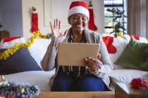 Glückliche afrikanisch-amerikanische Seniorin mit Weihnachtsmannmütze, die ein Weihnachts-Videotelefon mit dem Tablet macht. Weihnachten, Fest und Kommunikationstechnologie. — Stockfoto