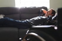 Homem caucasiano deficiente dormindo no sofá em casa. conceito de deficiência e deficiência — Fotografia de Stock