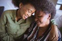 Sorrindo mulher sênior afro-americana com filha adulta abraçando com os olhos fechados. tempo de família em casa juntos. — Fotografia de Stock