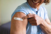 Середня частина інваліда, який показує своє вакциноване плече вдома. вакцинація для запобігання спалаху коронавірусу концепція — стокове фото