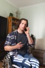 Kaukasischer behinderter Mann, der im Rollstuhl sitzt und zu Hause mit dem Smartphone spricht. Behinderten- und Behindertenkonzept — Stockfoto