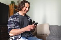 Caucasian disabled man sitting on wheelchair smiling while using smartphone at home. disability and handicap concept — Stock Photo