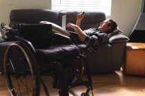 Uomo disabile caucasico che utilizza il computer portatile mentre sdraiato sul divano a casa. concetto di disabilità e handicap — Foto stock