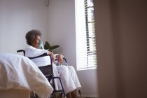 Femme âgée afro-américaine assise en fauteuil roulant avec masque à oxygène à la maison. soins de santé et mode de vie pendant la pandémie de covide 19. — Photo de stock