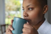 Relaxed african american plus size woman drinking coffee at home. lifestyle, leisure and spending time at home. — Stock Photo
